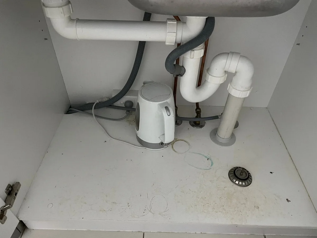 Under-sink cupboard with grime and marks before cleaning